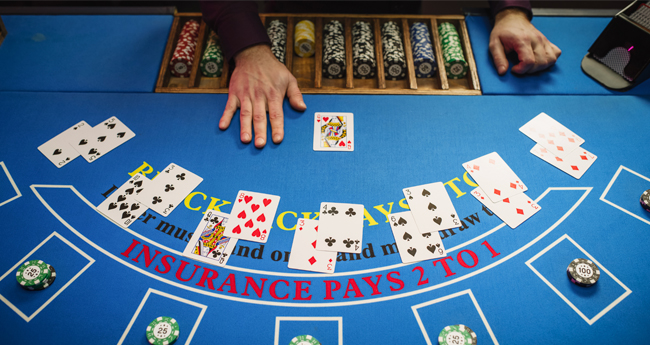 overhead image of a casino blackjack table with a game being player. It shows the dealer hand as well as the hands of 7 different player all facing up. 